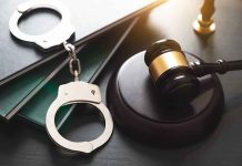 Gavel, handcuffs, and books on a table.