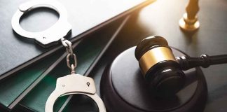 Gavel, handcuffs, and books on a table.