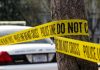 Police tape surrounding a tree and police car.