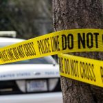 Police tape surrounding a tree and police car.