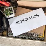 Envelope labeled RESIGNATION atop office supplies in box