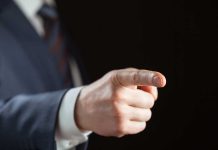 Person pointing with finger, wearing a suit.