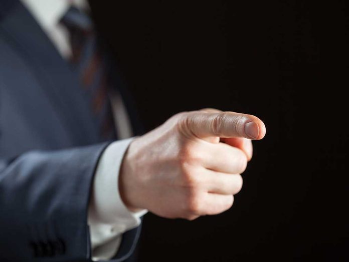 Person pointing with finger, wearing a suit.