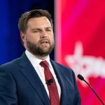 Man in suit speaking at conference podium