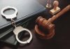 Gavel, handcuffs, and books on a table.