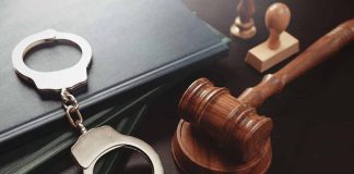 Gavel, handcuffs, and books on a table.