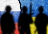 Silhouettes against Russian and Ukrainian flags with crack