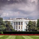 White House front view with dark clouds above.