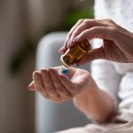 Person pouring pills from a small amber bottle