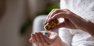 Person pouring pills from a small amber bottle