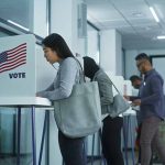 People voting in booths at a polling station.