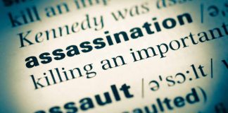 Close up of dictionary page defining assassination