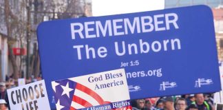 Pro-life marchers holding various anti-abortion signs.