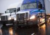 Two trucks driving on a wet road