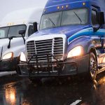 Two trucks driving on a wet road