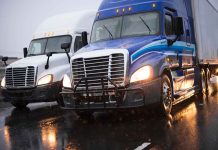 Two trucks driving on a wet road