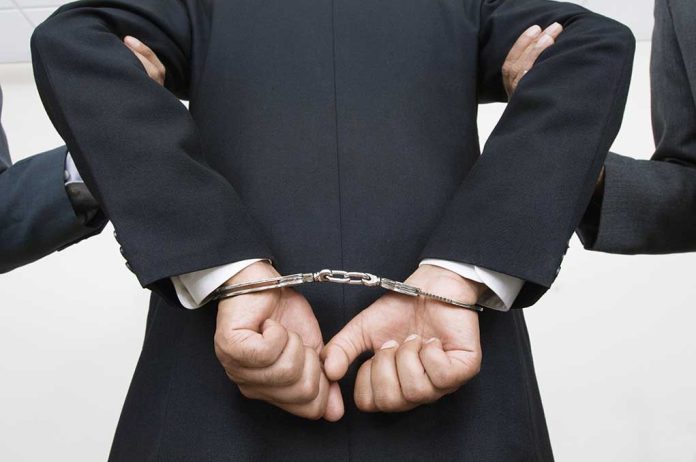 121141399 featured image Person handcuffed in suit escorted by two others