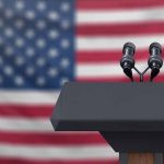 Podium with microphones in front of American flag