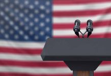 Podium with microphones in front of American flag