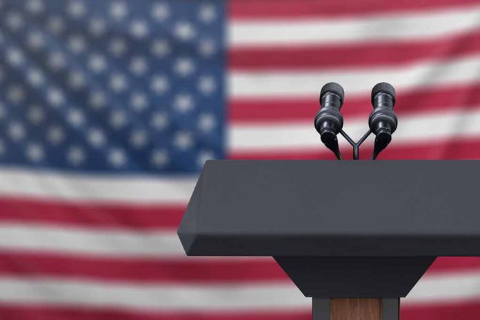1223942518 featured image Podium with microphones in front of American flag