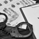 Handcuffsfingerprint sheets and clipboard on a desk