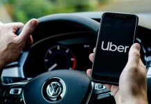 Person holding phone with Uber app inside car