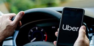 Person holding phone with Uber app inside car