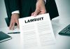 Person holding a document titled LAWSUIT in office