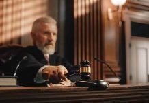 Judge holding gavel in a courtroom setting.