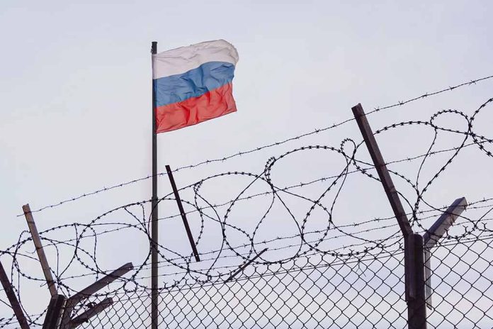 2148395873 featured image Barbed wire fence with Russian flag in background.