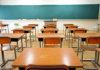 Classroom with wooden desks and empty green chalkboard