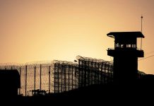 Sunset behind prison fence and guard tower