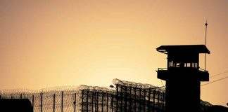 Sunset behind prison fence and guard tower