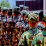 Soldiers in camouflage uniforms marching in formation outdoors