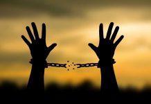 Hands breaking free from chains at sunset
