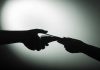 Silhouette of hands exchanging money in dim light