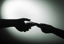 Silhouette of hands exchanging money in dim light