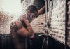 Person standing under flowing shower water indoors