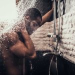 Person standing under flowing shower water indoors