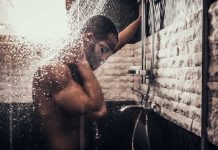 Person standing under flowing shower water indoors