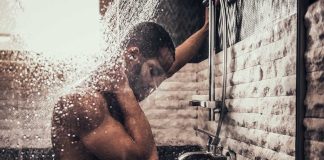 Person standing under flowing shower water indoors