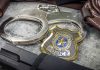 Handcuffs officer badge and firearm on textured surface