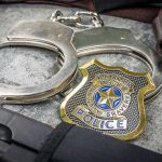 Handcuffs officer badge and firearm on textured surface