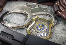 Handcuffs officer badge and firearm on textured surface