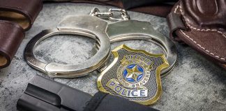 Handcuffs officer badge and firearm on textured surface