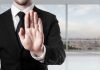 Person in suit with hand raised in stop gesture