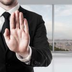 Person in suit with hand raised in stop gesture