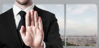 Person in suit with hand raised in stop gesture