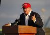 Person speaking at a podium wearing a red hat