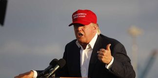 Person speaking at a podium wearing a red hat
